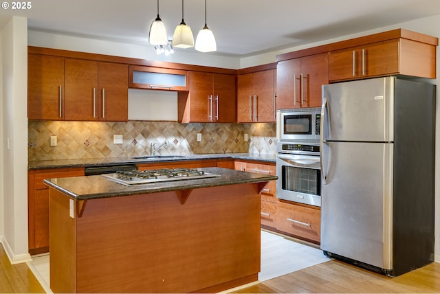 kitchen with sink, a kitchen breakfast bar, a center island, stainless steel appliances, and light wood-type flooring