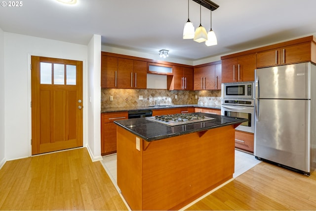 kitchen with sink, a breakfast bar area, appliances with stainless steel finishes, backsplash, and light hardwood / wood-style floors