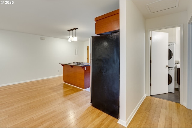 kitchen with stacked washer and dryer, a breakfast bar, stainless steel appliances, light hardwood / wood-style floors, and decorative light fixtures