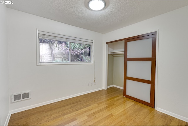 unfurnished bedroom featuring a textured ceiling, light hardwood / wood-style floors, and a closet