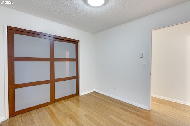 unfurnished room featuring a textured ceiling and light hardwood / wood-style flooring