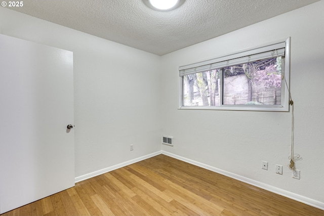 spare room with hardwood / wood-style floors and a textured ceiling