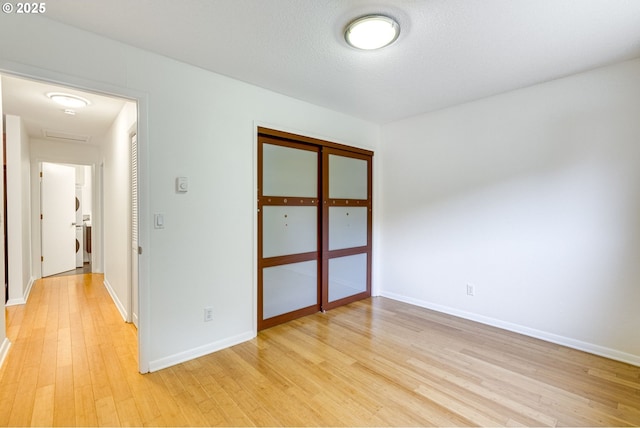 unfurnished room featuring a textured ceiling and light wood-type flooring