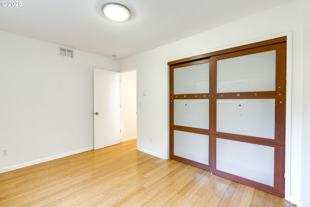 spare room featuring a textured ceiling and light hardwood / wood-style flooring