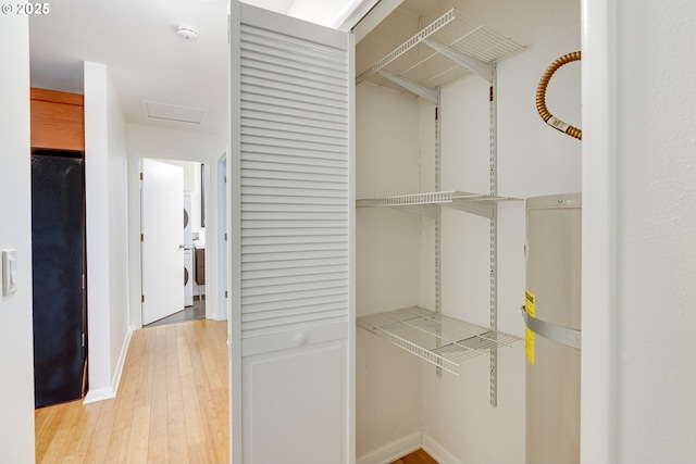 spacious closet with washer / clothes dryer and light wood-type flooring