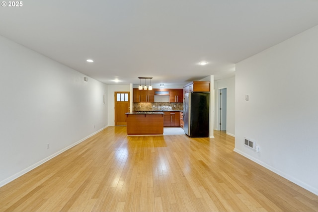 unfurnished living room with an inviting chandelier and light hardwood / wood-style floors