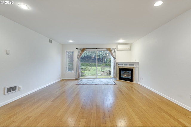 unfurnished living room with light wood-type flooring and an AC wall unit