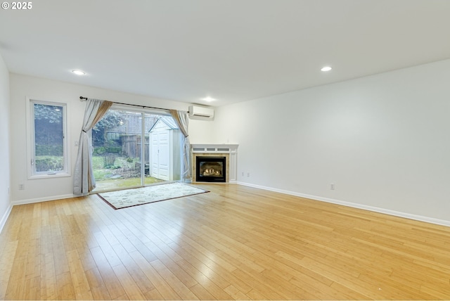 unfurnished living room featuring a wall mounted air conditioner and light wood-type flooring