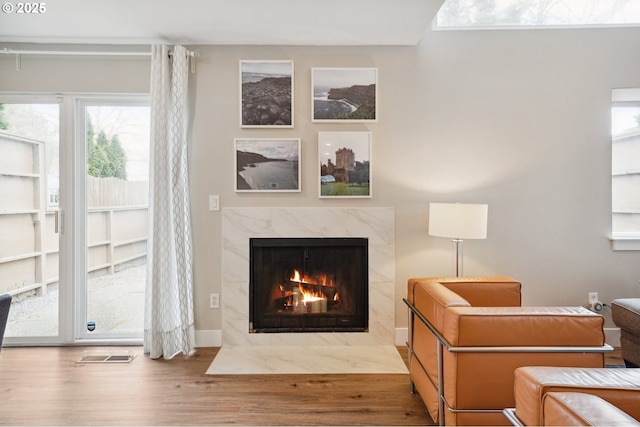 living area featuring visible vents, wood finished floors, and a high end fireplace