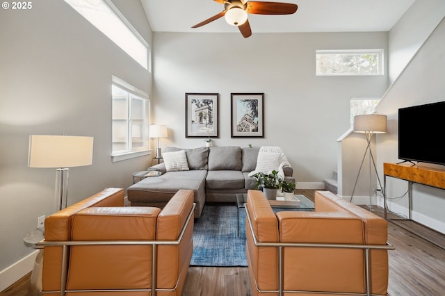 living area featuring wood finished floors, baseboards, and ceiling fan