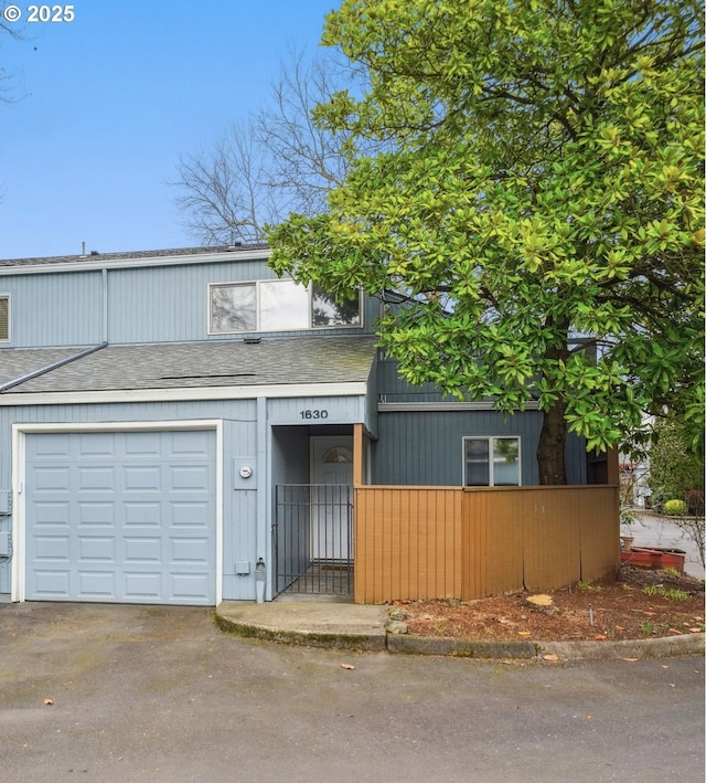 view of property featuring aphalt driveway, a garage, and roof with shingles