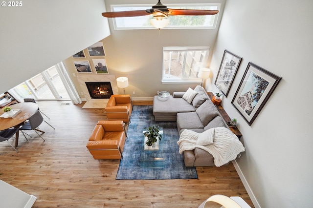 living room with a high end fireplace, plenty of natural light, a high ceiling, and wood finished floors