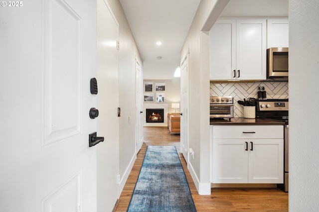 corridor featuring baseboards and light wood-style flooring