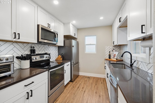1630 NW Eastbrook Ct, Beaverton, OR 97006 - kitchen featuring appliances with stainless steel finishes, dark countertops, light wood-style flooring, decorative backsplash, and recessed lighting