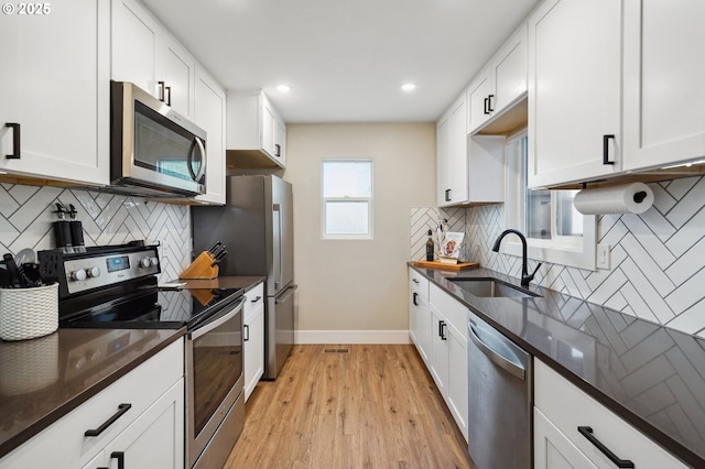 kitchen featuring a sink, stainless steel appliances, white cabinets, decorative backsplash, and baseboards