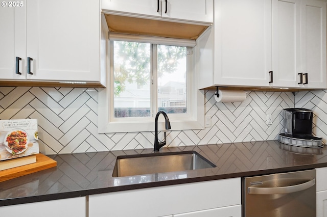 kitchen with a sink, dark countertops, stainless steel dishwasher, and white cabinets