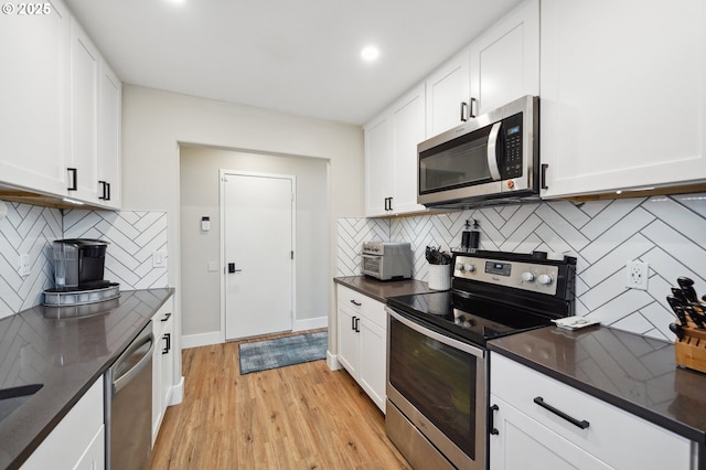 kitchen with light wood-type flooring, appliances with stainless steel finishes, white cabinets, and decorative backsplash