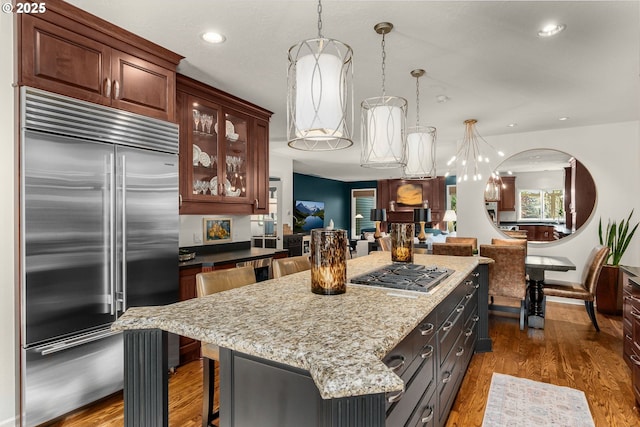 kitchen featuring a kitchen island, light stone counters, recessed lighting, appliances with stainless steel finishes, and wood finished floors