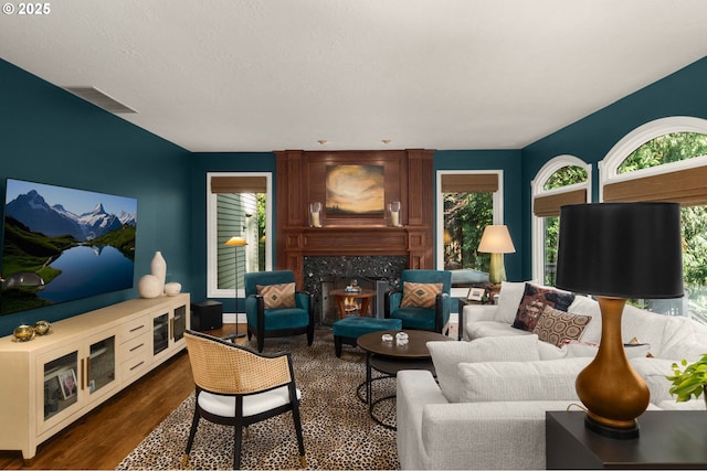 living area featuring a high end fireplace, visible vents, and dark wood-type flooring