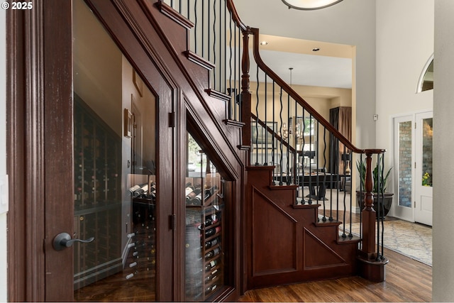 entryway with a wealth of natural light, a high ceiling, wood finished floors, and stairs