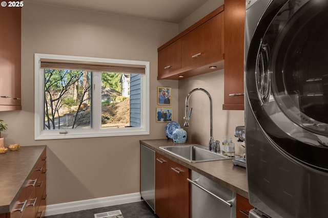 kitchen with visible vents, a sink, brown cabinetry, washer / dryer, and dishwasher