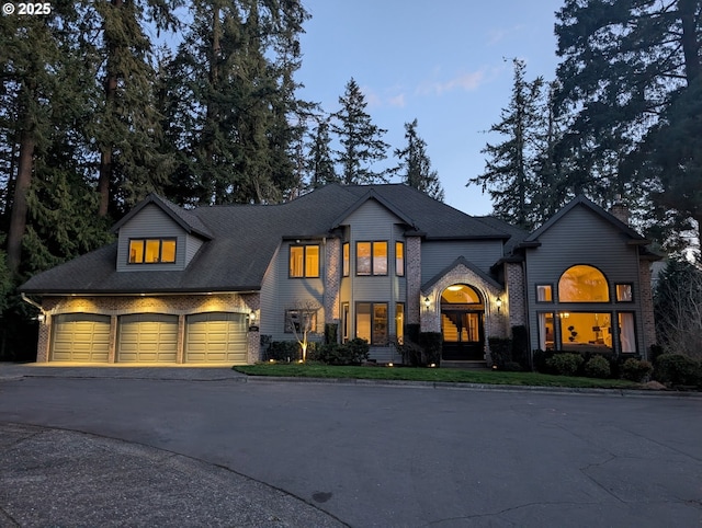 view of front facade with brick siding, an attached garage, and aphalt driveway