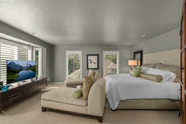 bedroom with visible vents, light colored carpet, and a textured ceiling