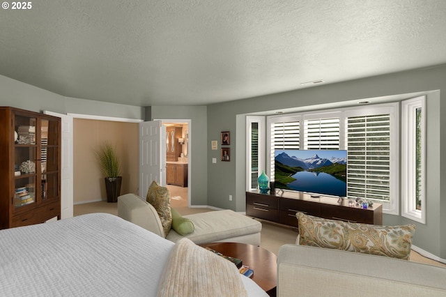 bedroom with visible vents, baseboards, carpet floors, ensuite bathroom, and a textured ceiling