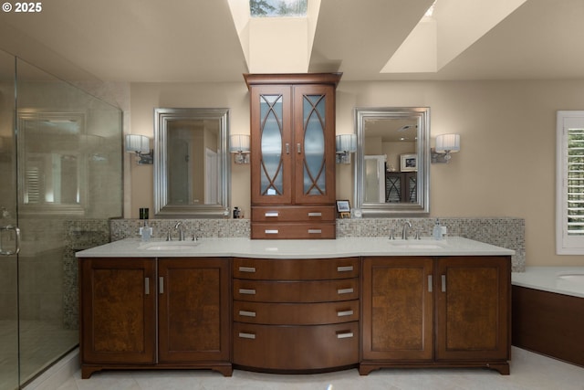 full bath with decorative backsplash, double vanity, a skylight, and a sink