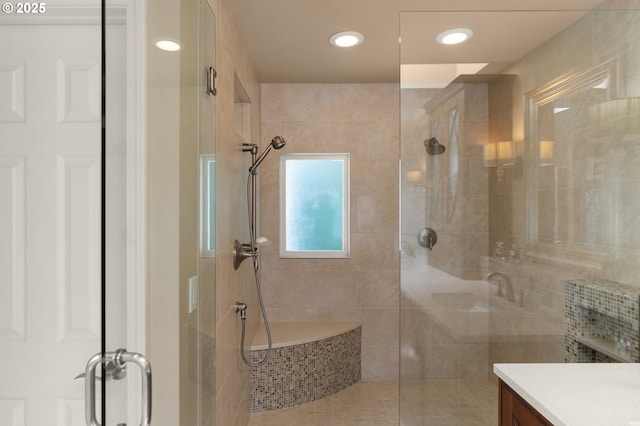 bathroom featuring a tile shower, recessed lighting, and vanity