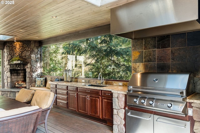 view of patio featuring a sink, area for grilling, exterior kitchen, and an outdoor living space with a fireplace