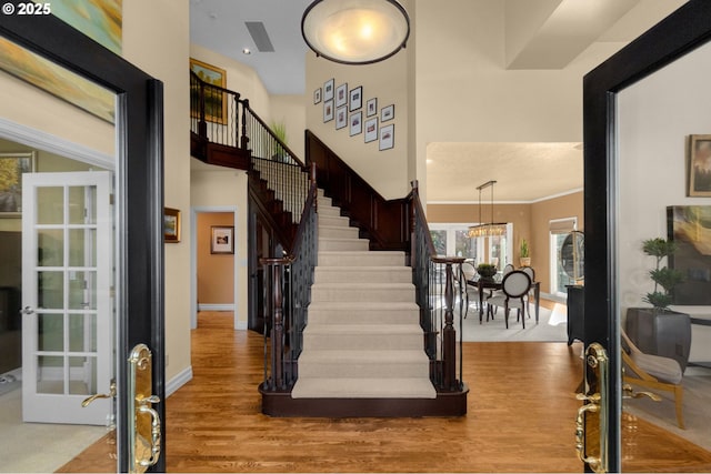 entryway featuring stairway, baseboards, light wood finished floors, an inviting chandelier, and ornamental molding