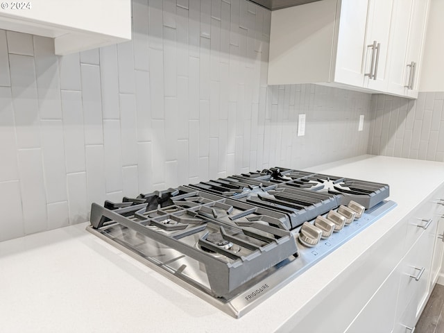 details with tasteful backsplash, white cabinets, and stainless steel gas cooktop