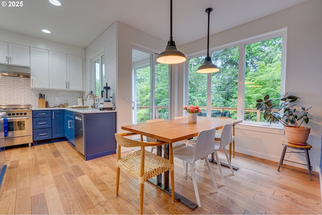 kitchen featuring stainless steel appliances, blue cabinetry, under cabinet range hood, healthy amount of natural light, and recessed lighting