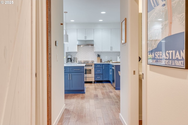 kitchen featuring high end stainless steel range oven, blue cabinetry, backsplash, under cabinet range hood, and light wood-style floors