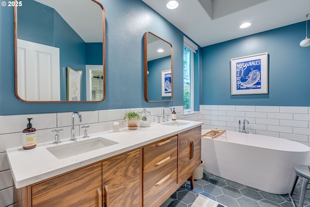 bathroom featuring tile walls, tile patterned flooring, a soaking tub, double vanity, and recessed lighting