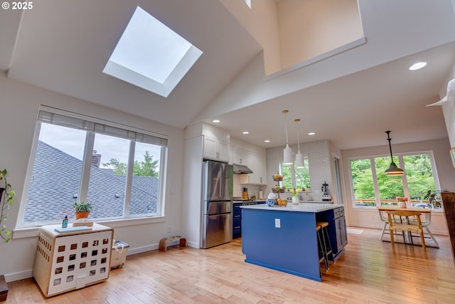 kitchen with stainless steel appliances, a center island, light countertops, light wood-style floors, and a skylight