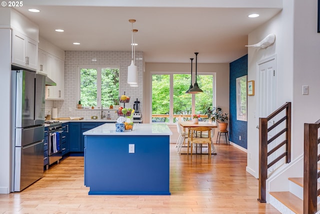 kitchen with appliances with stainless steel finishes, light countertops, blue cabinets, light wood-style flooring, and recessed lighting
