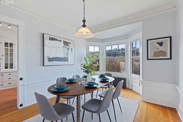 dining room with radiator, crown molding, and light wood-type flooring