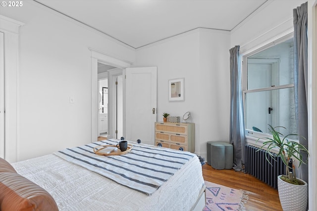 bedroom featuring radiator heating unit, ornamental molding, and hardwood / wood-style floors