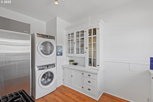 clothes washing area featuring stacked washer and clothes dryer and light hardwood / wood-style floors