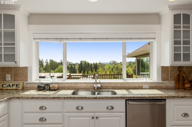 kitchen with stainless steel dishwasher, a sink, decorative backsplash, and white cabinets