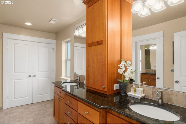 full bath featuring a sink, tile patterned floors, double vanity, and a notable chandelier