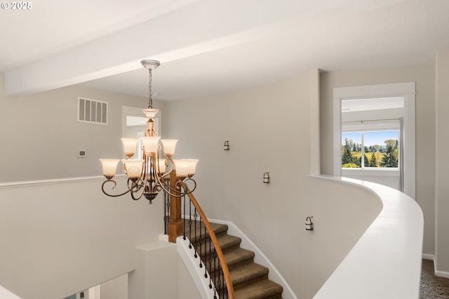stairway with visible vents, baseboards, and a chandelier