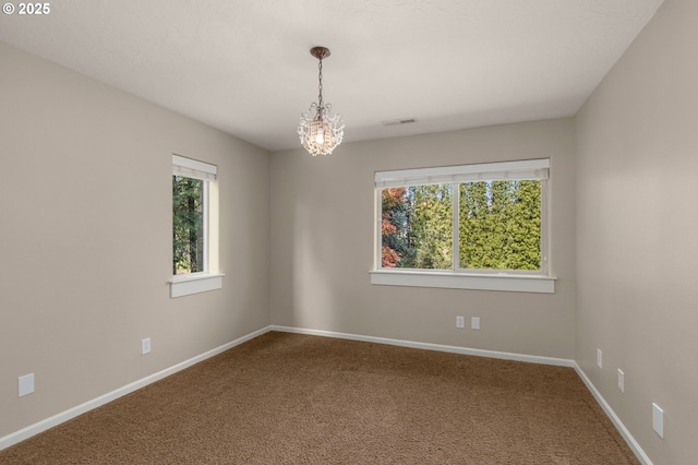 carpeted spare room featuring baseboards, a chandelier, and visible vents