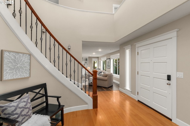 foyer with recessed lighting, baseboards, wood finished floors, and stairway