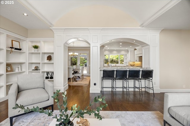 sitting room featuring an inviting chandelier, arched walkways, vaulted ceiling, and dark wood-type flooring