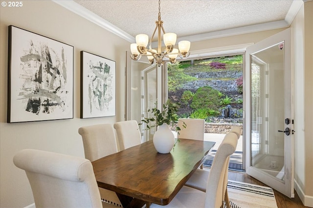 dining area featuring a textured ceiling, crown molding, wood finished floors, baseboards, and a notable chandelier