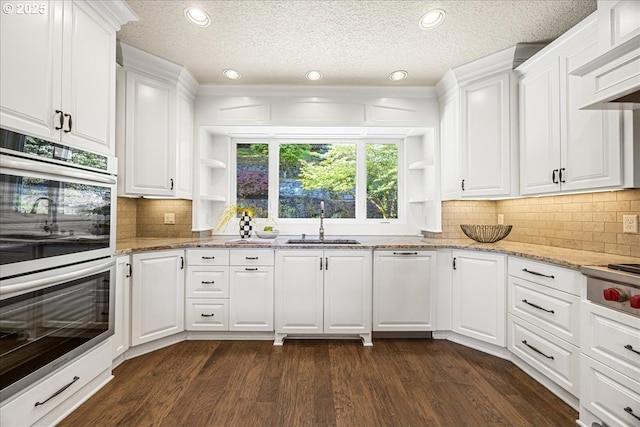 kitchen featuring open shelves, stainless steel double oven, a sink, and dark wood finished floors