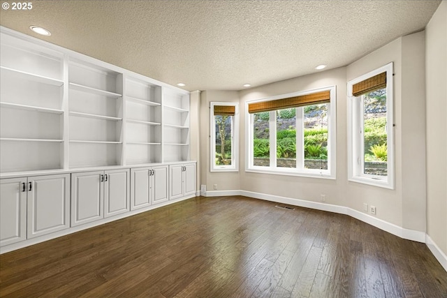 spare room with a textured ceiling, baseboards, recessed lighting, and dark wood-style floors